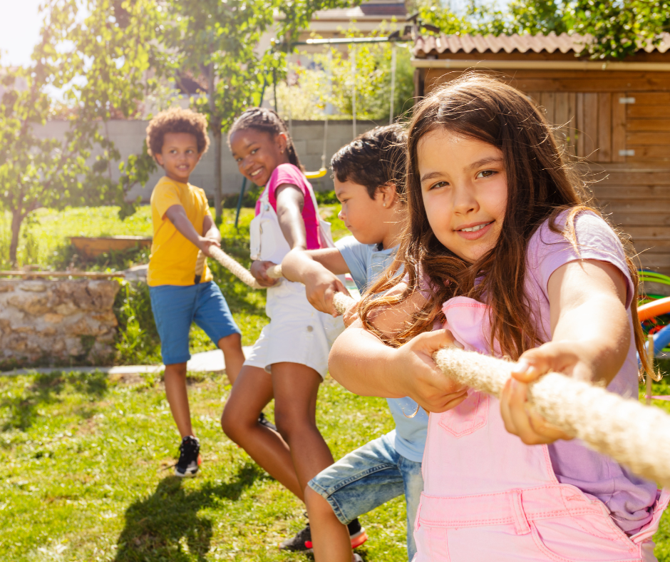 Four children play an outdoor rope game at summer camp.