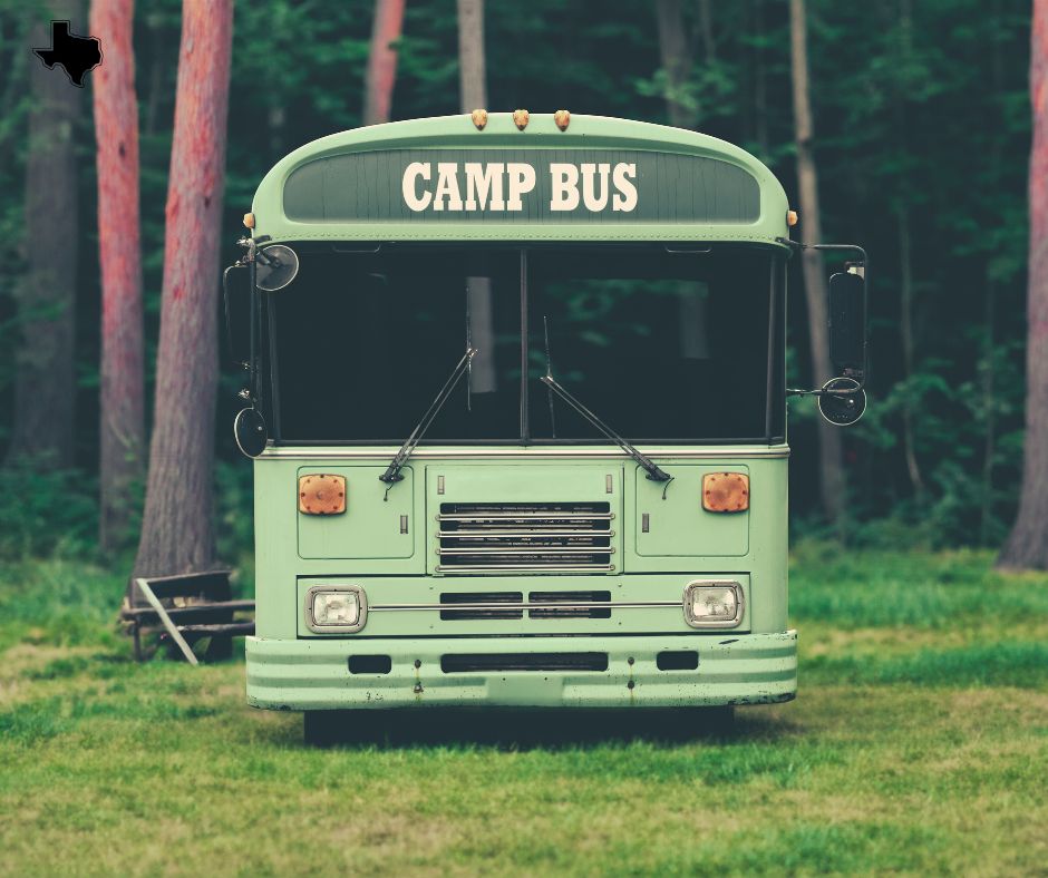 A green bus stands still in a wooded area, representing affordable summer camp options in DFW.