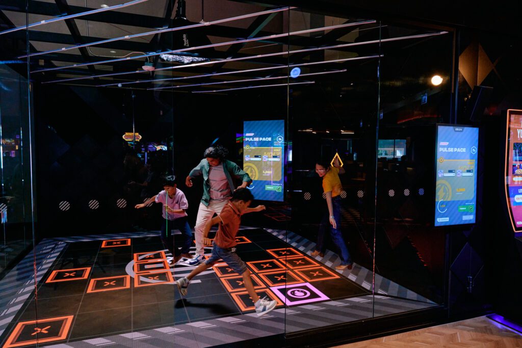 Friends and family engaged in games at Dave & Buster's, a vibrant venue for kid-friendly activities in Dallas at night.