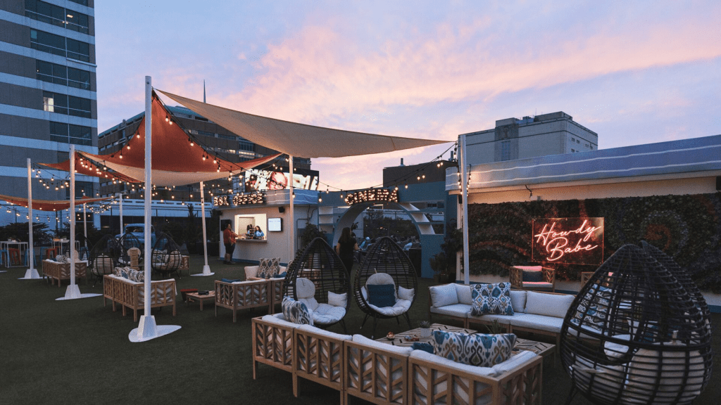 A rooftop patio featuring lounge chairs and umbrellas, perfect for family-friendly evening activities in Dallas.