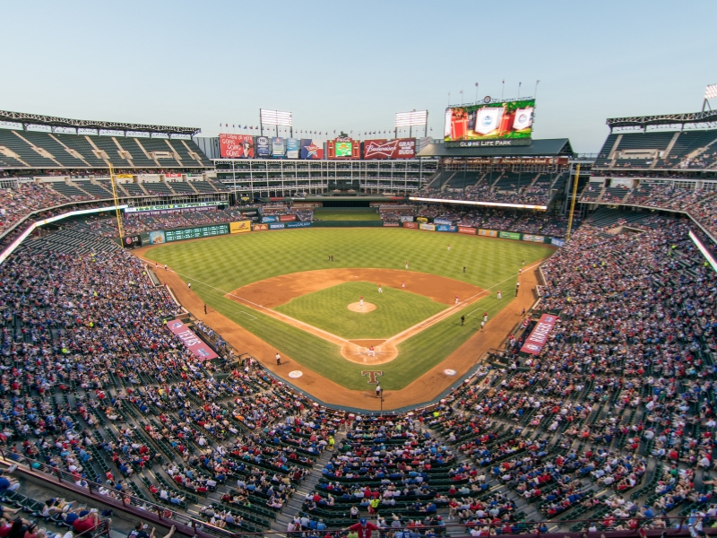 A lively baseball stadium packed with fans, capturing the excitement of a night event in Dallas.