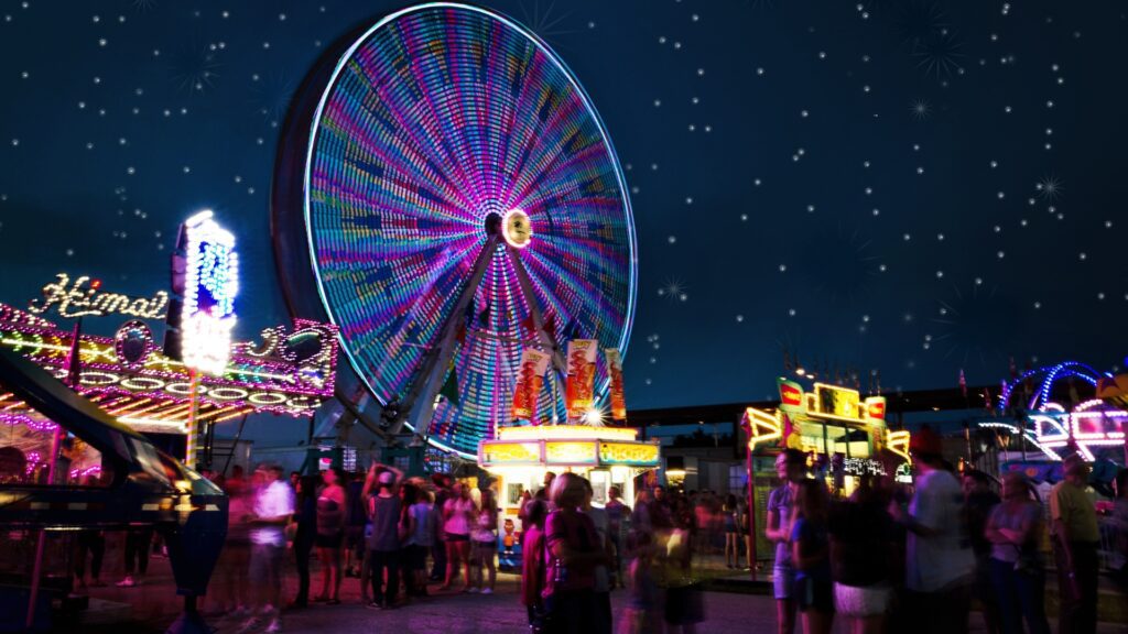 A vibrant carnival scene at night featuring a lit ferris wheel, perfect for family fun in Dallas.