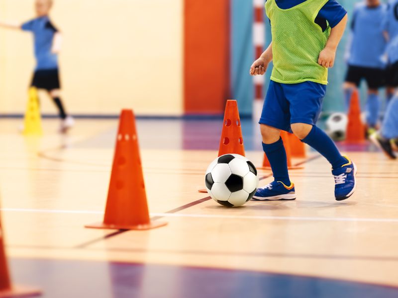 A young boy practices soccer skills with cones while playing youth futsal in North Texas.
