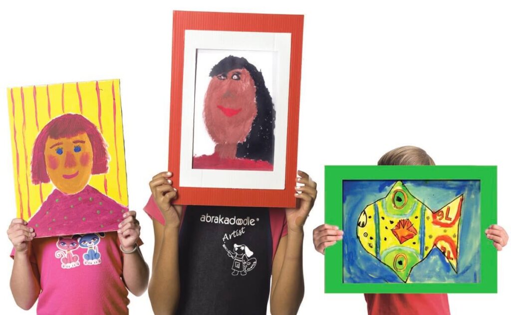 Three children show off framed images of their faces, emphasizing the value of process art in developing creativity and confidence.